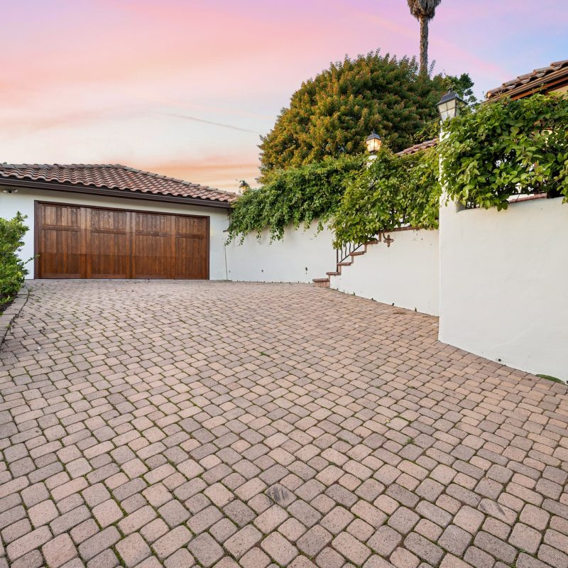 a driveway with brick pavers, and a garage in the background a driveway with brick pavers, and a garage in the background